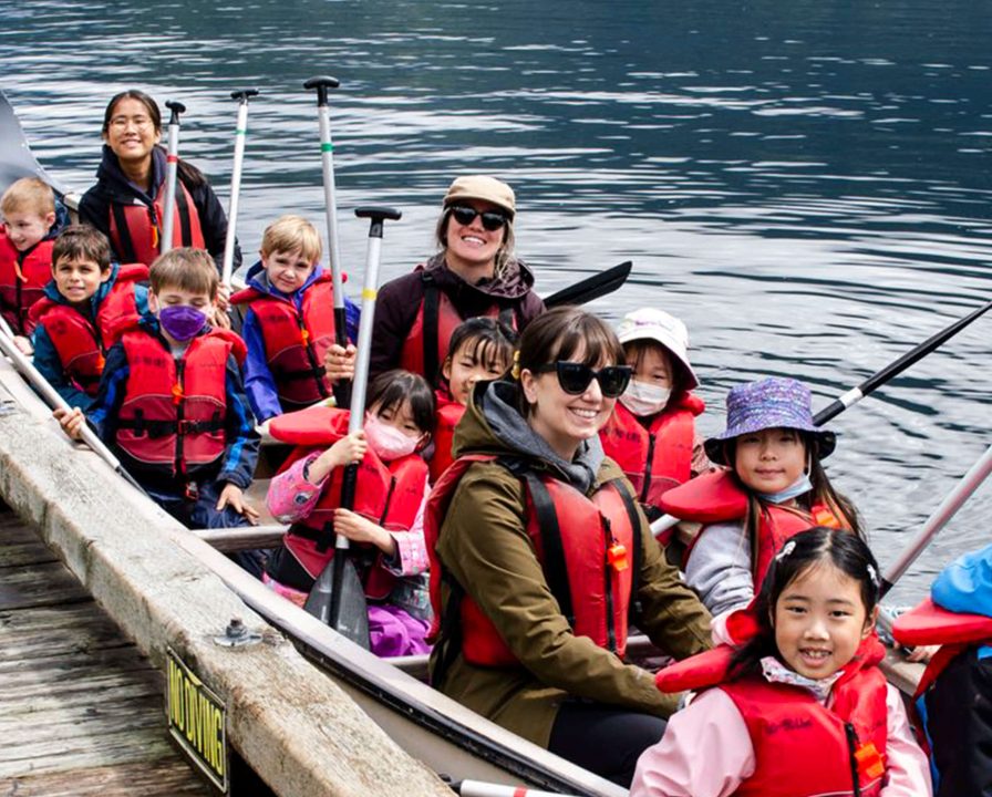 Two teachers and a group of Junior School students on a boat, as part of a field trip